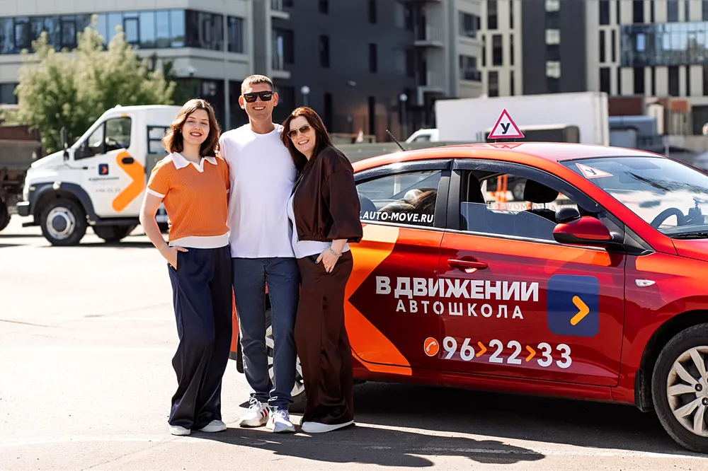 Выпускники и инструктор у учебной машины